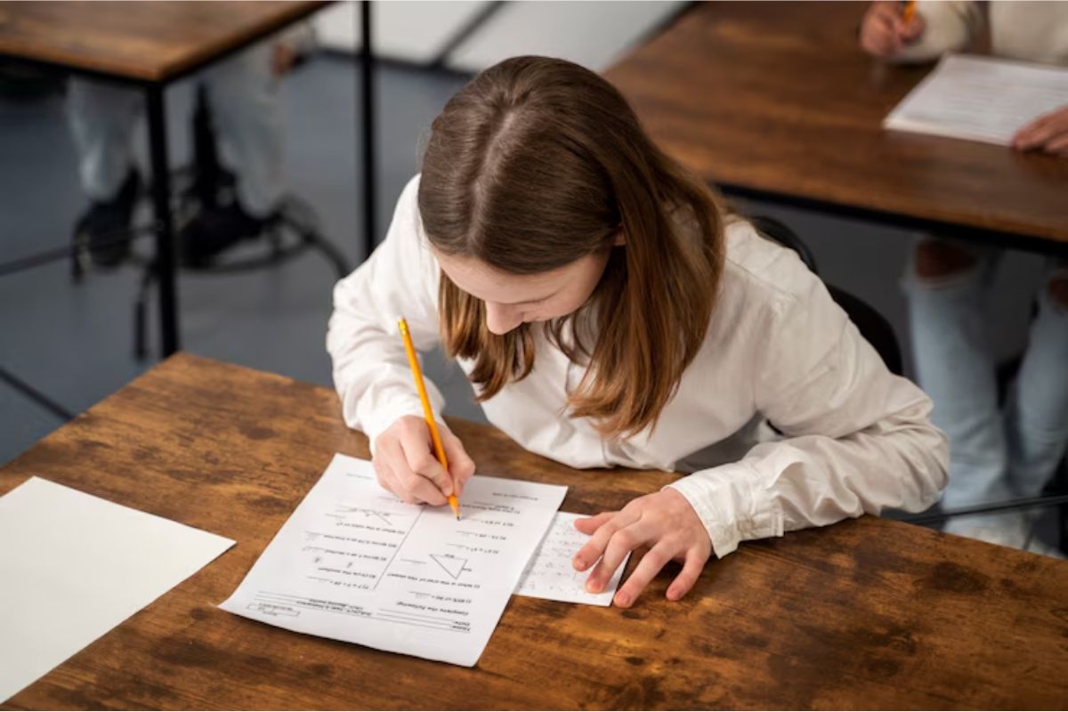 Uma menina está estudando com um simulado. Ela se prepara em uma sala de aula