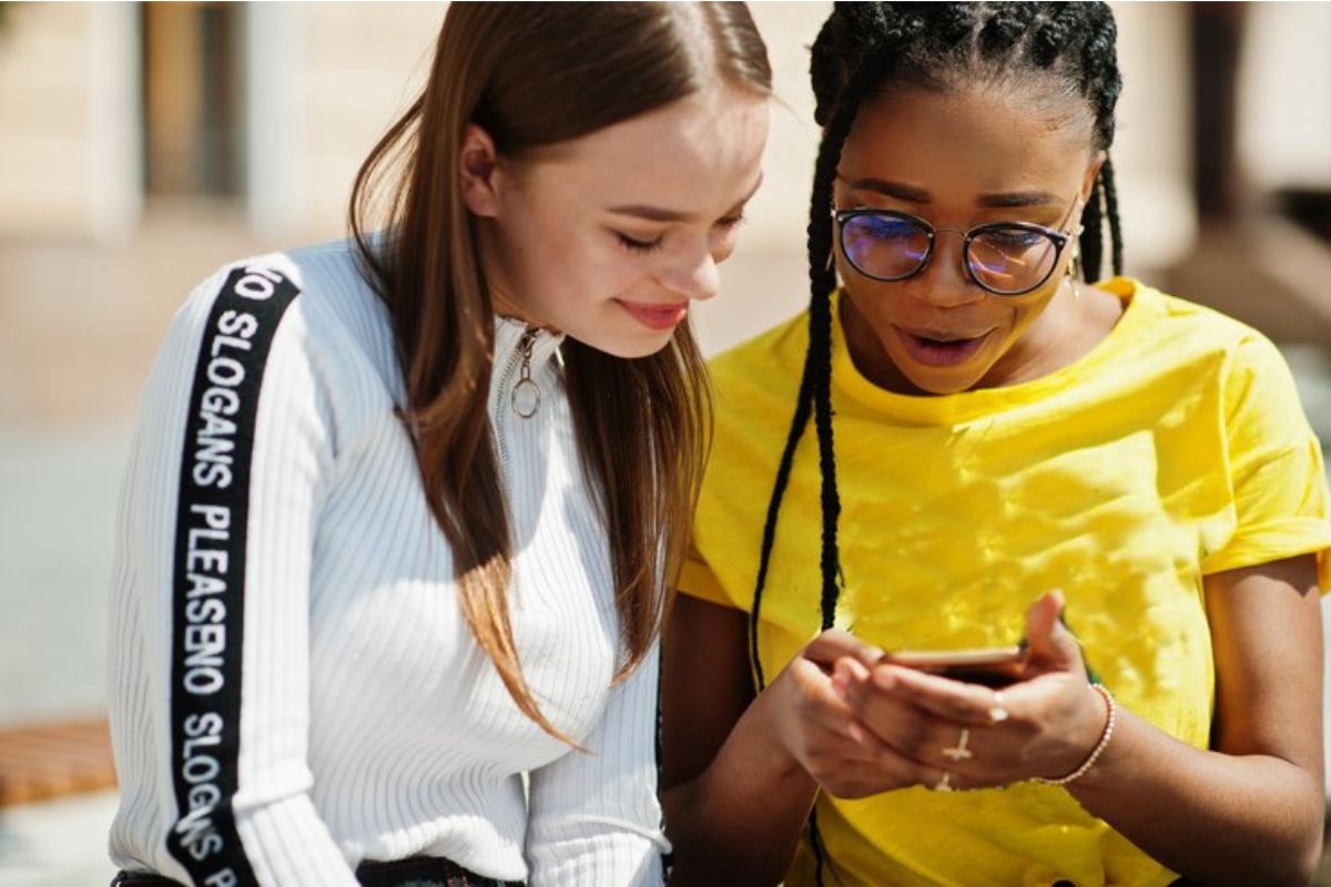 Duas meninas olham para o celular onde observam os detalhes do Vestibular Unesp 2025