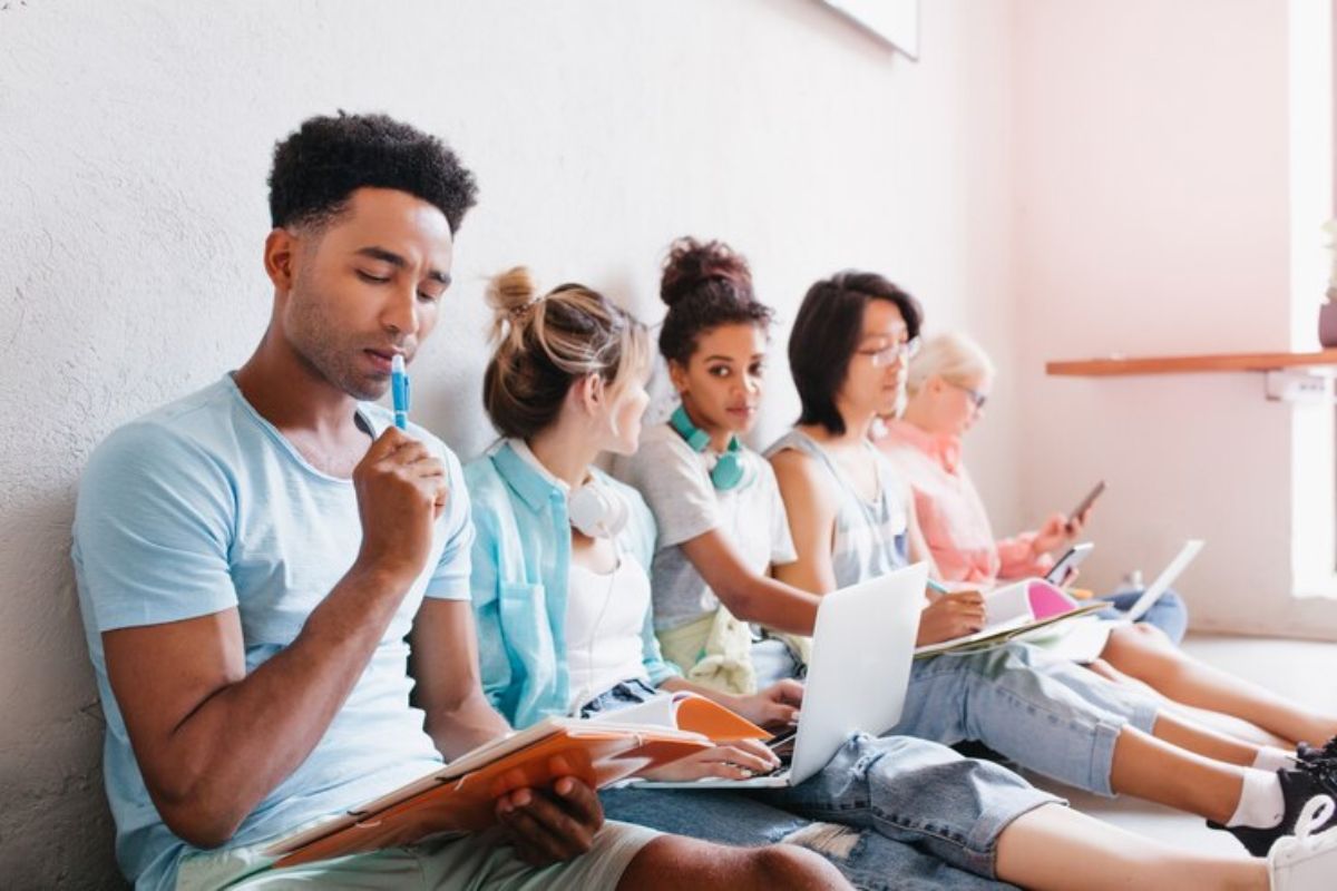 Um grupo de estudantes sentados no chão. Eles se preparam para o Vestibular Univesp 2025