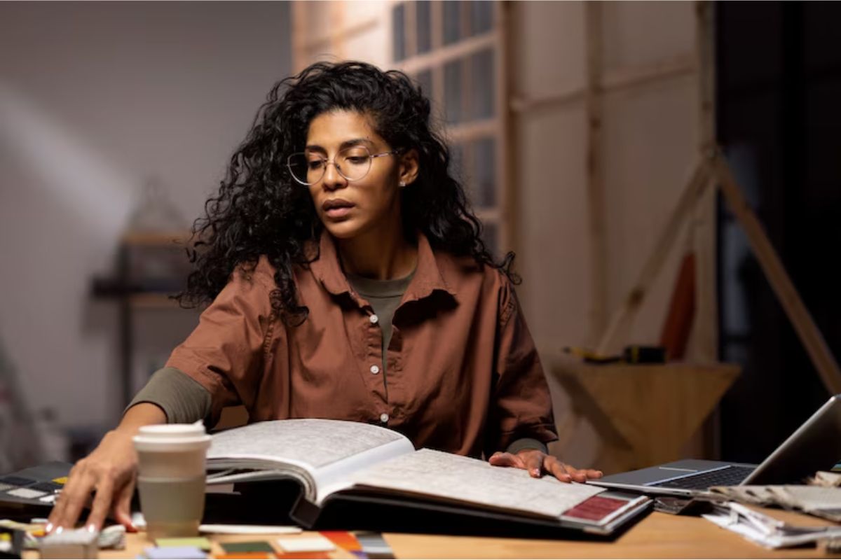 Uma menina em sua mesa de estudos se prepara para ProUni 2025. Há diversos materiais na mesa e ela olha para um caderno aberto