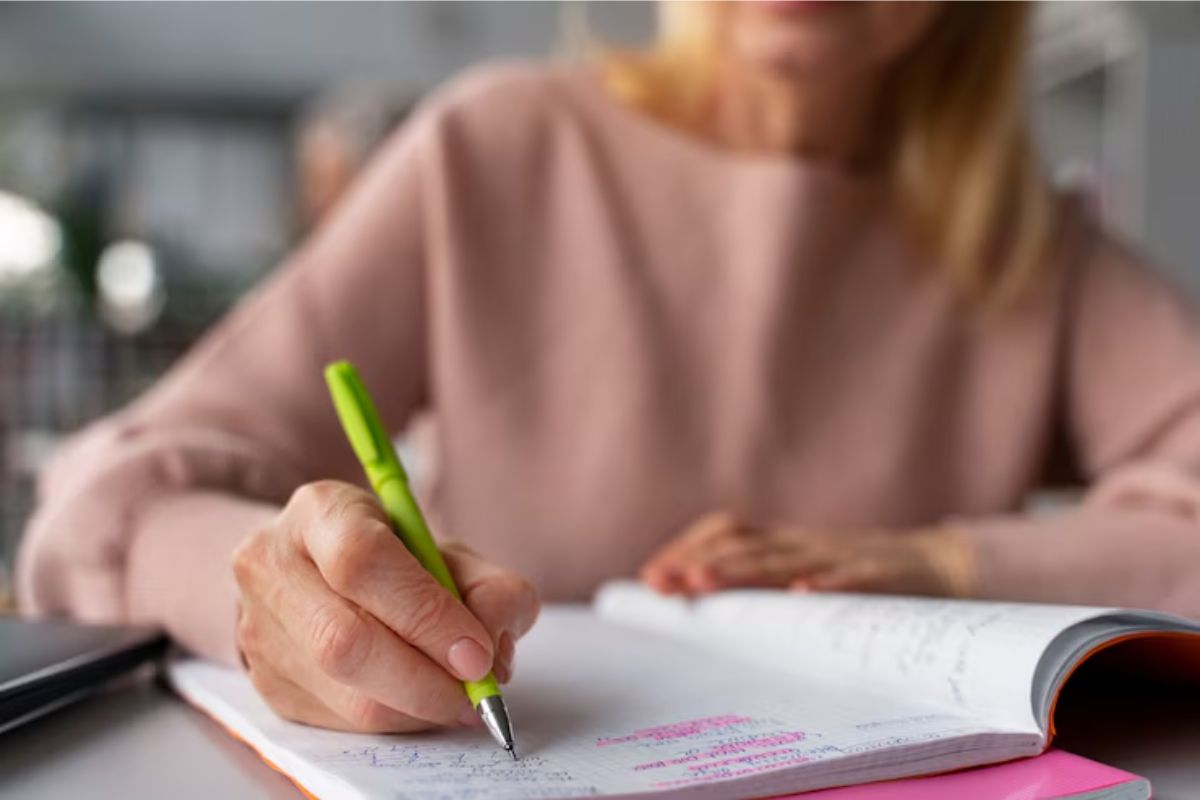 Uma menina está escrevendo em seu caderno. Ela estuda dentro sala de aula