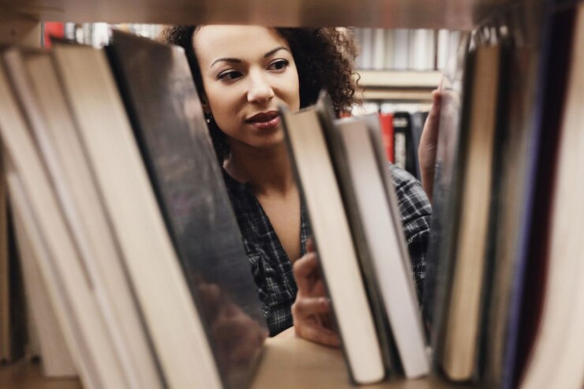 Uma estudante procura um livro na biblioteca para se preparar para o Vestibular UEL 2025