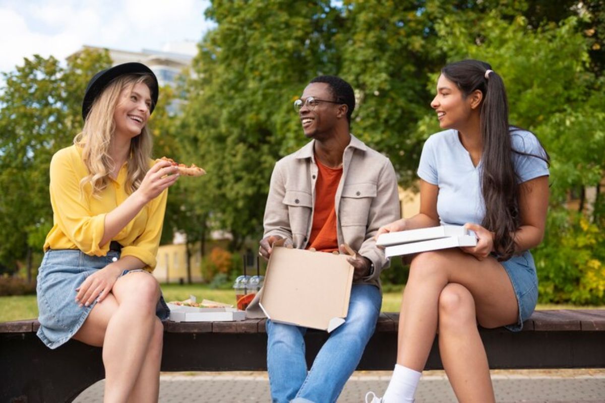 Três colegas sentados em um banco conversam sobre o Vestibular UNIP 2025