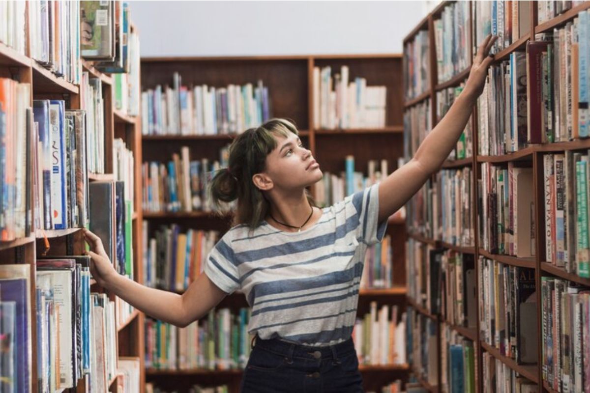 Uma estudante no corredor da biblioteca procura por livros que vão cair no Vestibular UEL 2025