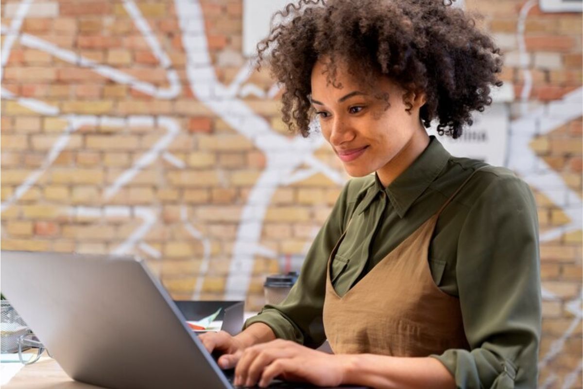 Uma estudante sentada usando o seu notebook para fazer a Dilatação FIES 2025