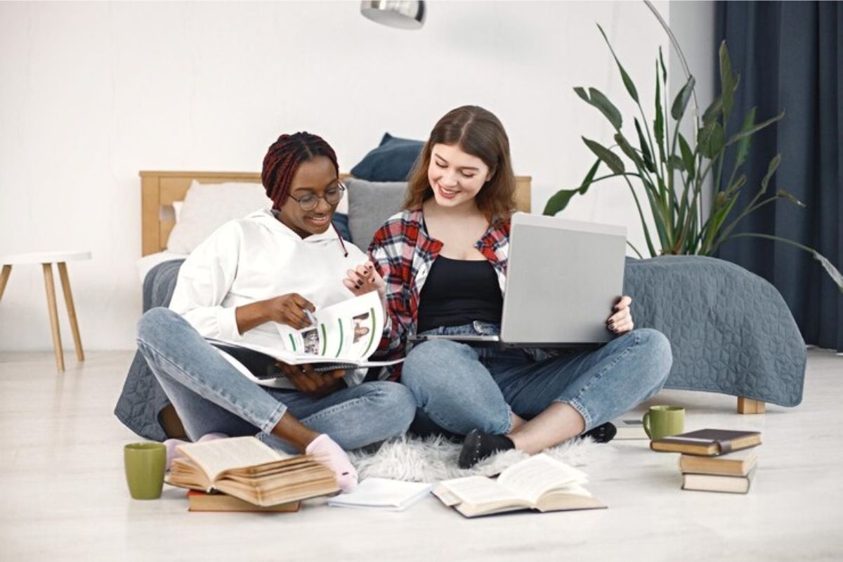 estudantes sentadas no chão com notebook no colo