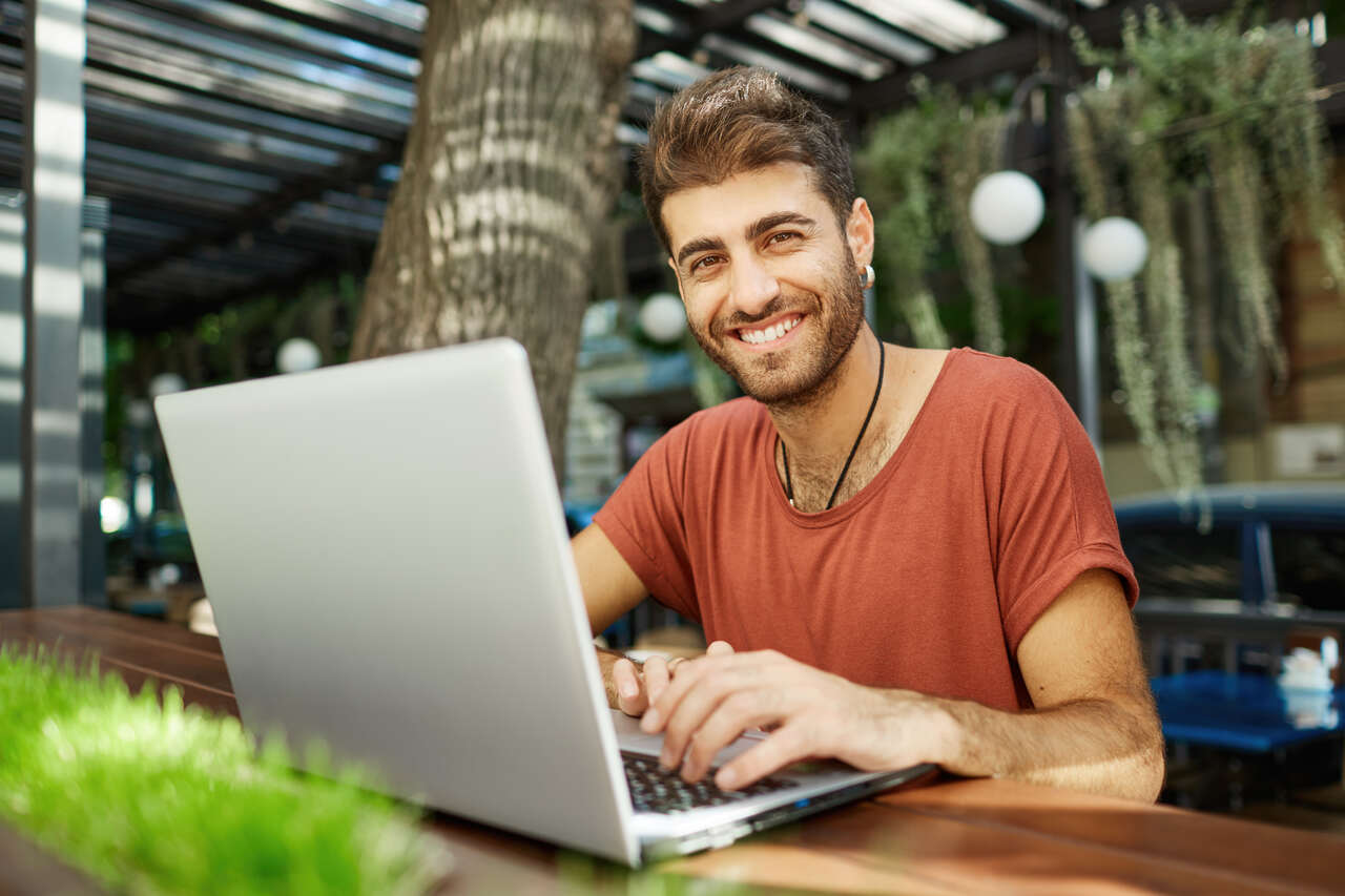 Jovem estudando no notebook posa sorridente 