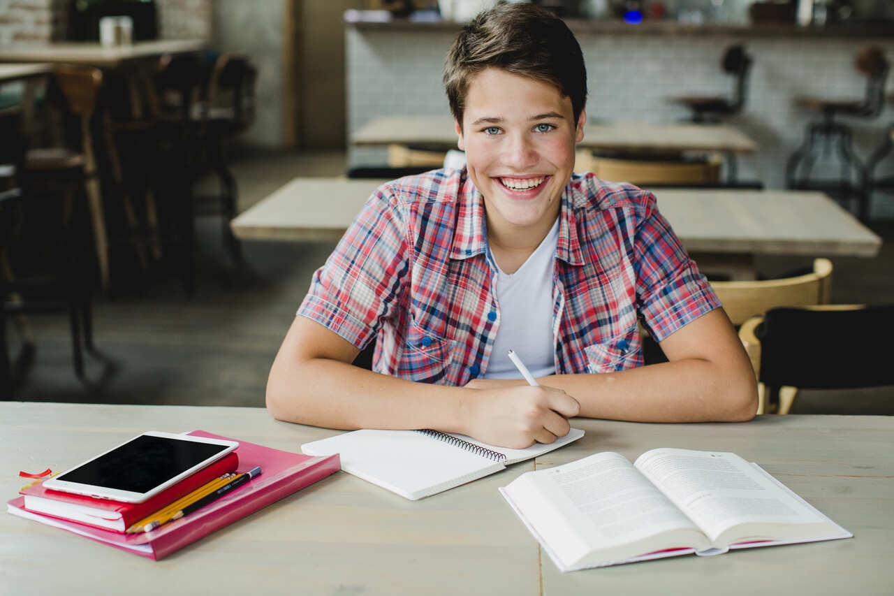 Adolescente posa sorridente durante a aula